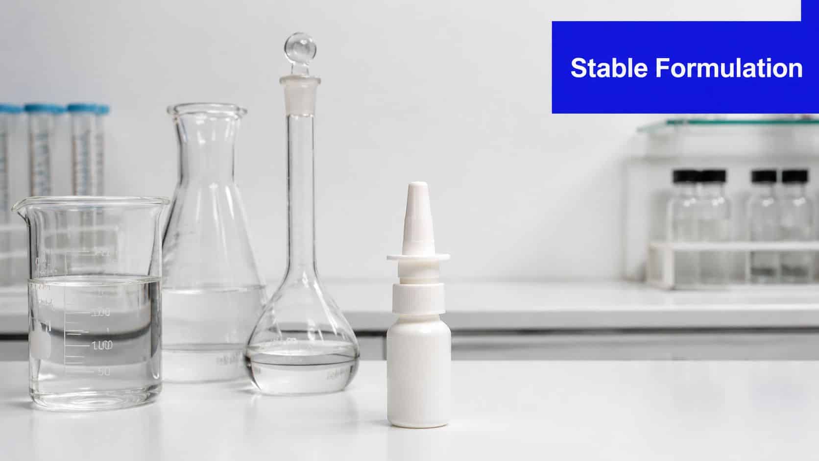 A nasal spray bottle stands on a white laboratory table next to various clear glass chemical containers.