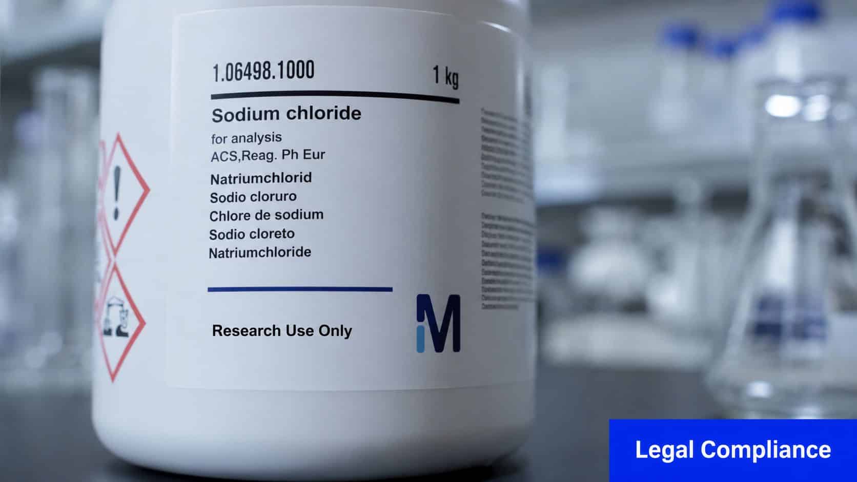 A close-up view of a chemical reagent bottle labeled Sodium Chloride sitting on a laboratory workbench.